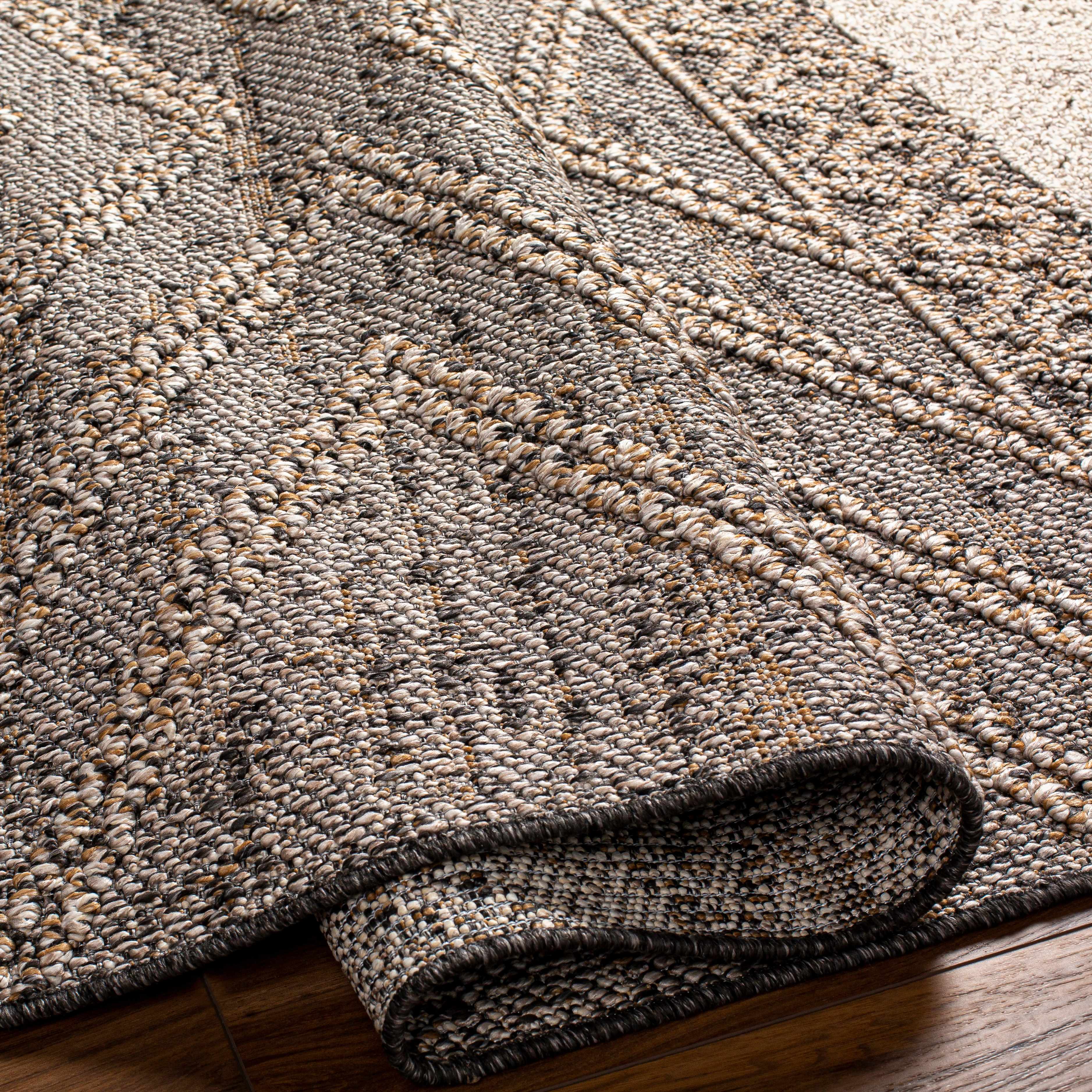 Close-up of the Beige Charcoal Areli Area Rug showing geometric patterns and textured weave with black, mustard, and taupe colors. Fold