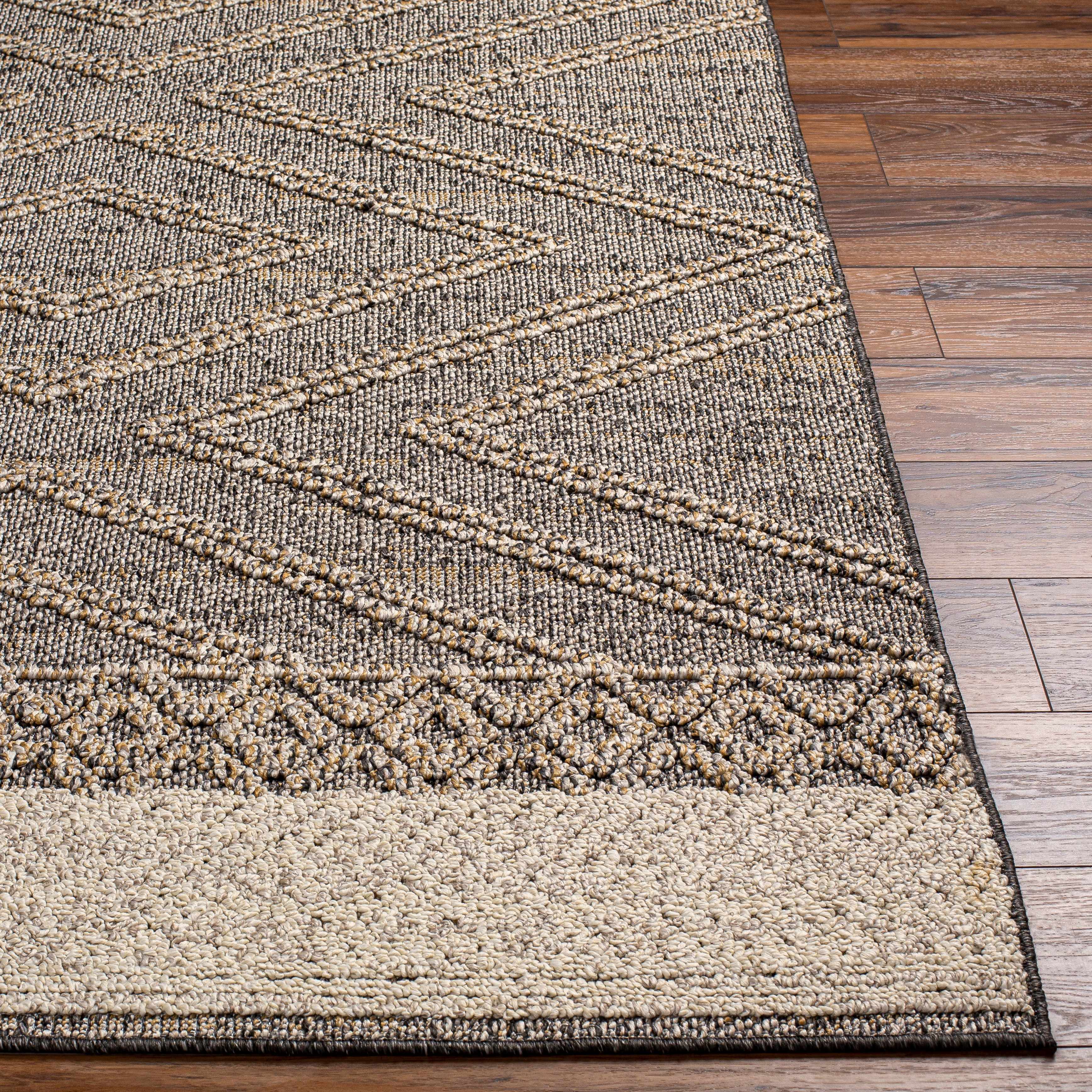 Close-up of Beige Charcoal Areli Area Rug showing geometric pattern and textured weave on wood floor. Front