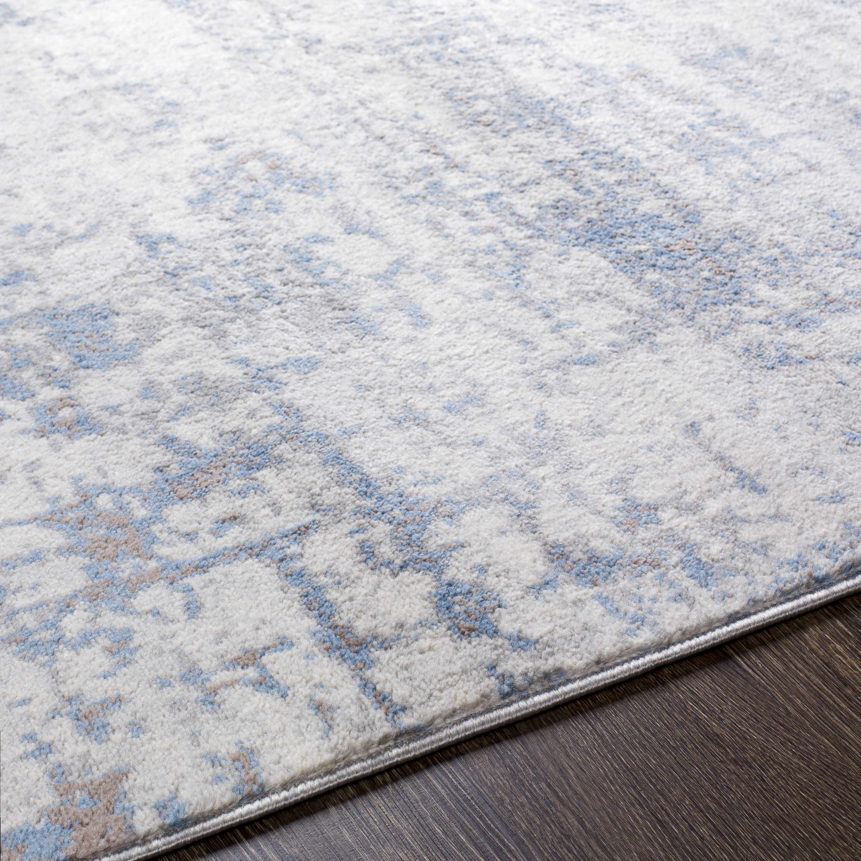 Close-up of the Texanna Abstract Blue/Gray Area Rug showing its light blue, gray, and off-white abstract pattern and soft texture. Texture