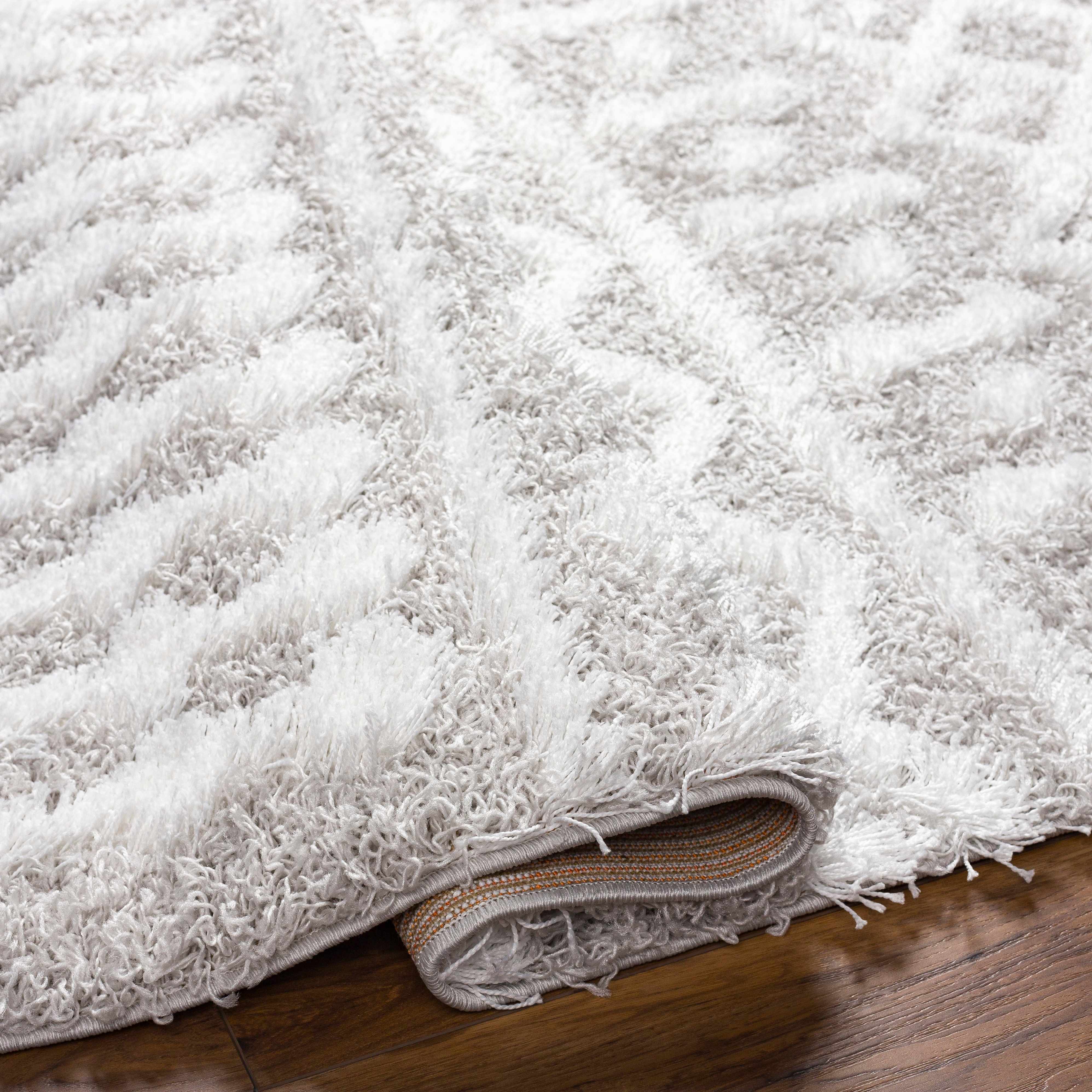 Close up of the light gray Vernonburg Shag Area Rug showing its soft texture and subtle geometric pattern. Fold