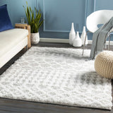Living room scene with a light gray Vernonburg Shag Area Rug, cream sofa, white chair, and blue accent wall. Roomscene-Rectangle
