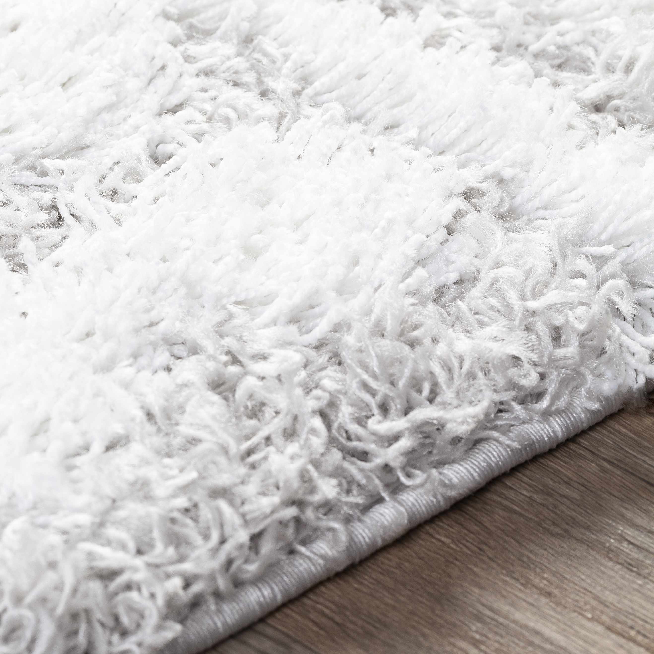 Close up of a plush Vernonburg Shag Area Rug in light gray and white, showing texture. Texture