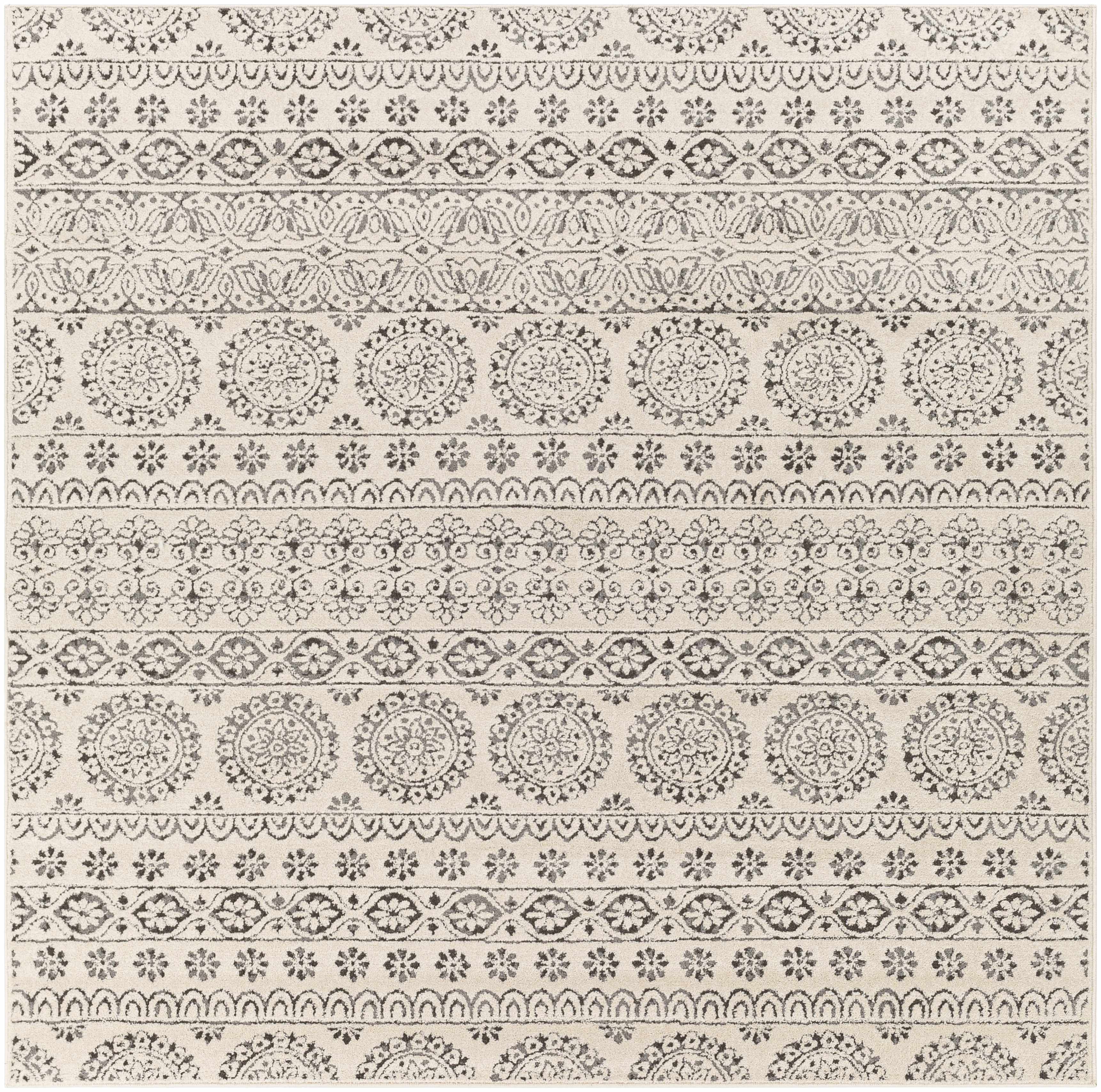 Close up of the Warroad Area Rug. Beige rug with charcoal, gray, and light beige bohemian-style pattern. Design-Square-7