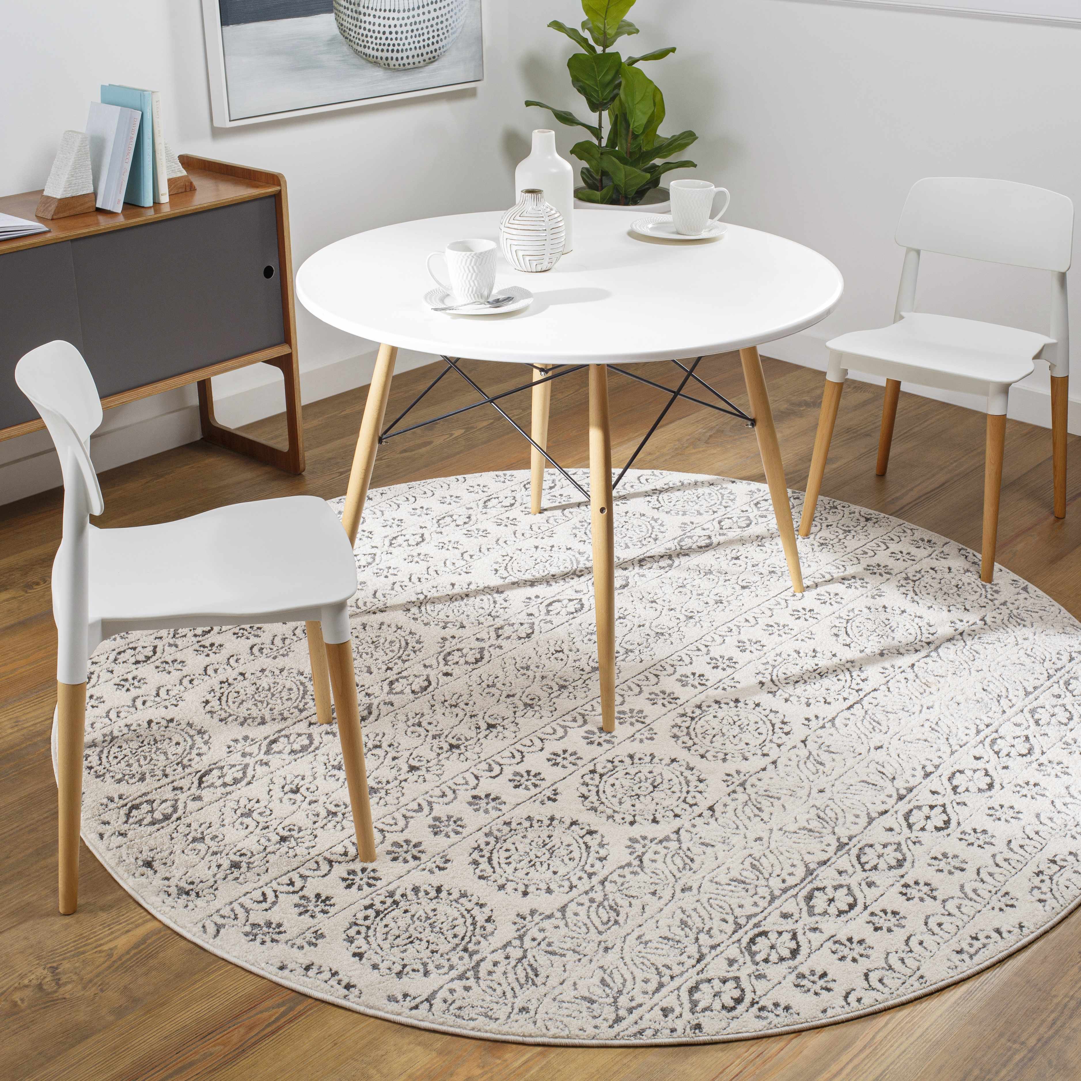 Dining room scene with a round white table on a round, light beige and charcoal Warroad Area Rug. Roomscene-Round